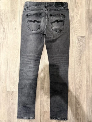 Nudie Jeans Lean Dean Jeans Grå W29/L32 - Slim Tapered Fit - Nudie Lean Dean grå (Mono Grey) jeans med slim tapered fit passform som sitter smalt men bekvämt och funkar till allt, storlek W29/L32, midja 39 cm, ytterbenslängd 105 cm, benöppning 15 cm, modellen är 185cm & väger 65kg, i fint skick.