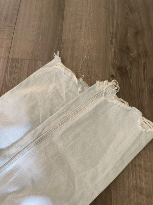 Ljusblå raka jeans med rå kant - Säljer ett par ljusblå jeans med rak passform och trendig rå kant nertill. Jeansen har klassisk femficksdesign och hög midja. Perfekta för en avslappnad och cool stil. Materialet är kraftig denim i bomull.