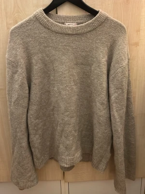 Beige stickad tröja med rund hals - Mysig beige stickad tröja med rund halsringning och ribbade muddar vid ärmslut och nederkant. Tröjan har en avslappnad passform och är tillverkad i ett mjukt material som passar perfekt för kyligare dagar. Från gina tricot barn avdelning. Storlek 170. Väl använd 