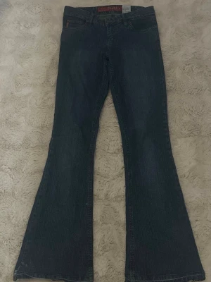 Mörk blåa Jeans Bootcut - Säljer ett par blåa bootcut jeans från Mudd med utsvängda ben. Jeansen har fem fickor, knappgylfuu och är gjorda i mjuk denim. Endast lite slitna lägst ner på benen, men annars är jeansen i perfekt form! Det står ingen storlek men passa mig perfekt som är runt 160cm.  Priset går att diskutera💕