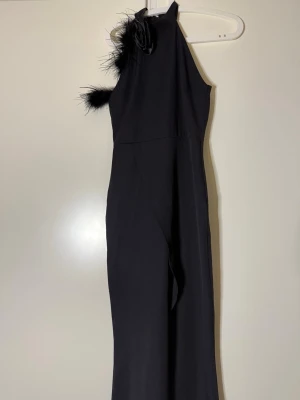 Svart elegant långklänning  - Säljer denna superfina eleganta svarta klänning. Vet ej märke, då den är köpt Vinted. Aldrig använd av mig utan endast testad. Lång klänning med fina fjäder och ros detaljer, samt slits vid benet (se sista bilden)💗