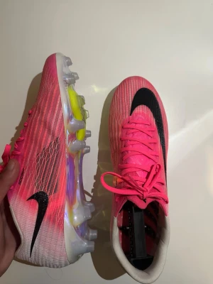 Nike Mercurial Superfly 11  - Säljer ett par Nike Mercurial fotbollsskor i en riktigt snygg rosa färg med svarta detaljer och stor svart Swoosh. Skorna har genomskinlig sula med dobbar och en ovandel i syntetmaterial som ger bra grepp på planen. Kommer med matchande skopåse och innersula.