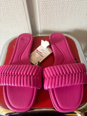 Rosa sandaler från Zara - Snygga och trendiga sandaler från Zara i en stark rosa färg. De har en fyrkantig tå och bred rem med coolt flätat mönster. Tillverkade i syntetmaterial och perfekta för att lyfta vilken outfit som helst.