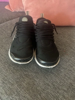 Nike air Max presto - Säljer ett par svarta Nike sneakers med vit sula och svarta skosnören. Skorna har en sportig design med mesh-överdel och plastdetaljer på sidorna. Perfekta för en streetwear-look och riktigt bekväma att ha på sig. Pris kan diskuteras också. Nike air presto äkta säljs bara under sommarn. 