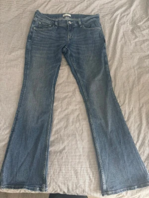 Blå lågmidjade bootcut jeans med mönster på bakfickorna från gina tricot  - Säljer ett par  blå bootcut jeans från med broderade bakfickor. Jeansen har fem fickor, låg midja och är tillverkade i mjuk denim. De är aldrig använda, endast provade😊 