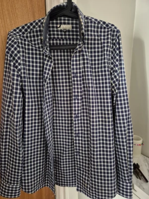 Blårutig skjorta från Dressmann - Säljer en klassisk blårutig skjorta från Dressmann i storlek S. Skjortan har lång ärm, knappar framtill och en tidlös krage. Perfekt för dig som gillar en stilren och enkel look. Materialet känns mjukt och bekvämt, troligen bomull.