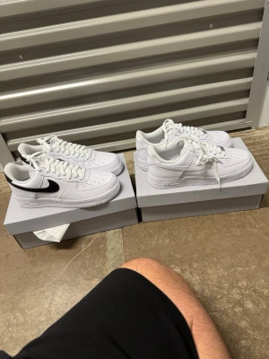 Nike Air Force 1 '07 sneakers, vit/svart & hel vita, strl42. - Helt nya oanvända Nike Air Force 1 '07 sneakers, vit/svart & hel vita, strl42.  Skorna har inte blivit använda eller testade. Nypris st 1400 kr (så 2800 kr totalt) hos Nike.   Original kartong medföljer