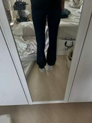 Mörkblå bootcut jeans - Säljer ett par mörkblå bootcut jeans med silverfärgad knapp. Jeansen är sydda från skinny till flare, man ser den andra färgen på jeansen. 
