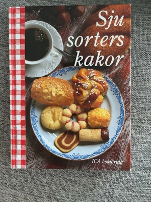 Sju sorters kakor ICA bokförlag - Klassisk svensk bakbok med färgstarkt omslag och rödvitrutigt mönster längs ryggen. Innehåller närmare 300 recept på kakor, bullar och tårtor. Perfekt för dig som älskar att baka och vill ha inspiration till både traditionella och moderna bakverk.