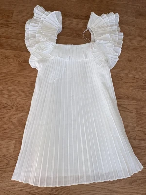 Vit plisserad klänning från Zara - Säljer denna populära och eftertraktade klänningen från Zara!! Så fin till student och liknande❤️