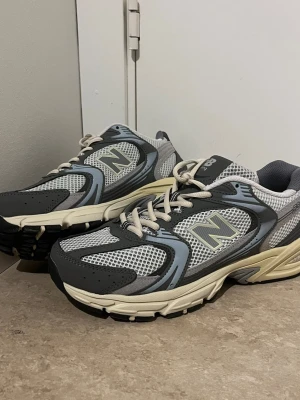 New Balance 990v3 grå sneakers - Snygga New Balance 990v3 sneakers i grått och vitt med mesh och mockadetaljer. Klassisk chunky sula i beige och svart. Ikoniska N-loggan på sidan och skön vadderad plös. Perfekta för dig som gillar retrostil och streetwear.