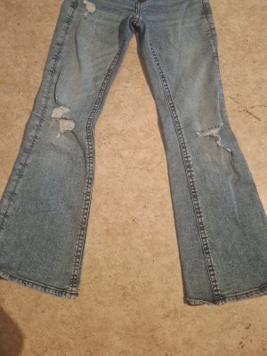 Blå bootcut jeans med slitningar - Säljer ett par ljusblå bootcut jeans från Gina Tricot young i storlek 158. Den perfekta jeansen om man vill ha något basic men snyggt!