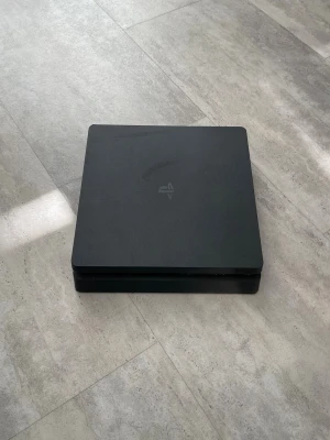 PlayStation 4 Slim med spel - Säljer en svart PlayStation 4 Slim från Sony i stilren, fyrkantig design. Medföljer gör spelen Far Cry 4 i blåt fodral från Ubisoft,  FIFA 23, FIFA 20. alla kablar som behövs tillkommer också.