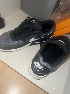 Nike Air Max 90 - Nike Air Max sneakers i svart och vitt med klassisk swoosh-logga på sidan och AIR-tryck bak. Ovandelen är i mesh och syntetmaterial, med svarta skosnören och vit sula med synlig Air-enhet. Perfekta för dig som gillar sportig och stilren look.  Helt oanvända max haft på mig dom 3-4 gånger.. Skick 10/10!🌟