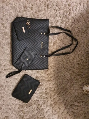 Svart shoppingväska med mönster - Snygg svart shoppingväska med guldfärgade detaljer. Perfekt för dig som gillar stilrena och praktiska väskor.