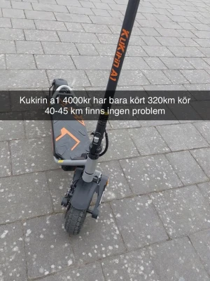 Kukirin A1 elscooter svart/orange - Elektrisk scooter Kukirin A1 i svart med orange detaljer. Utrustad med stor display, bred fotplatta och robusta däck. Perfekt för smidig transport i stan och har en sportig design med tydliga logotyper på styret och plattan.