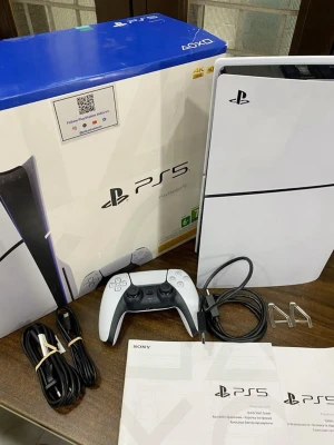 Sony PlayStation 5 konsol med tillbehör - PlayStation 5 konsol i vit och svart design med en DualSense-handkontroll, strömkabel, HDMI-kabel, USB-kabel, stativ och manualer. Konsolen har en futuristisk look med rundade kanter och matta ytor. Perfekt för gaming i toppklass.
