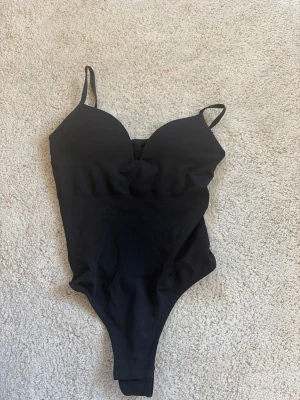 Svart body med tunna axelband H&M - Snygg svart body från H&M i storlek XS med tunna axelband och vadderade kupor. aldrig använd