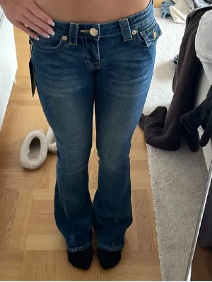 Blå bootcut jeans från True Religion - Säljer ett par blå bootcut jeans från True Religion i modellen joey. De är i nyskick aldrig använda och prislappen kvar. Jag säljer de på grund av att de var lite för tajta för mig .  Nypriset var 1400 och säljer för 1000. Storleken är 24 x 32 . Hör av er om ni har yttligare  frågor 💕