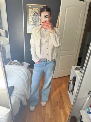 Vit jeansjacka  - Säljer en snygg vit jeansjacka från Bik Bok. Klassisk modell med raka linjer, två bröstfickor med lock och silverfärgade knappar framtill. Jackan har en avslappnad passform och är tillverkad i kraftigt jeanstyg. Den är fri från fläckar bortsett från lite missfärgning vid kragen, men det är inget som märks vid nedvikt!