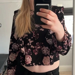 Svart blommig blus med volang - Säljder denna söta svarta blus med smuts-rosa blommor💕Den är i mycket bra skick och är ifrån KappAhl i storlek 158💕
