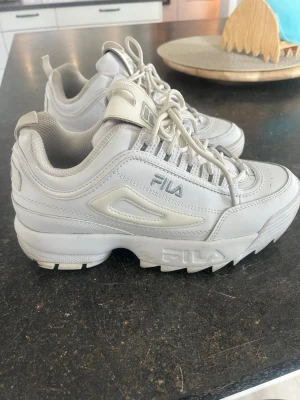 Vita chunky sneakers från Fila - Stilrena vita sneakers från Fila med chunky sula och klassisk logga på sidan och hälen. 