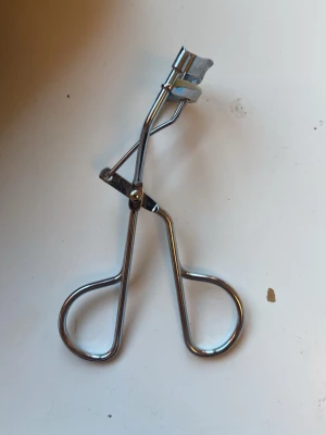 Ögonfransböjare från Depend silver - Säljer en klassisk ögonfransböjare från Depend i blankt silverfärgat metallmaterial. Böjaren har ergonomiska handtag och en vit silikonpad för skonsam böjning av fransarna. Perfekt för att få snyggt böjda fransar snabbt. Den säljs såklart nästan helt oanvänd, bara köpt eftersom jag ville testa, men det var obekvämt så jag säljer nu! 