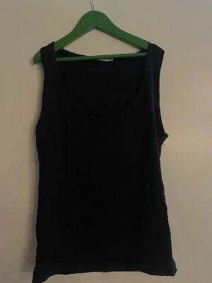 Svart linnetopp från Zara - En enkel och stilren svart linnetopp från Zara. Toppen är ärmlös med rund halsringning och har en klassisk passform som funkar till många olika looks. Perfekt att matcha med jeans, kjol eller shorts.