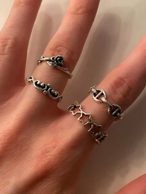 Set med fyra silvriga ringar - Säljer ett set med fyra silvriga ringar i olika designer. Ringarna har detaljer som stjärnor, en ros, snirkliga mönster och bokstäver. Alla ringar är i metall med vintageinspirerad look och passar perfekt för dig som gillar att mixa och matcha accessoarer. Ej äkta silver, alla för 20kr eller 5kr styck 🫶