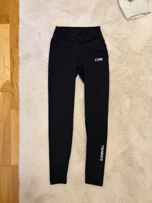 Svarta scrunch-leggings från ICANIWILL - Säljer ett par svarta leggings från ICANIWILL med hög midja och scrunch-detalj bak. Materialet är stretchigt och passar perfekt för träning. Logga finns på höften och längs benet. Snygga och bekväma för dig som gillar att röra på dig. OBS liten i storlek!! Skulle säga passar xxs-xxxs. Passar inte mig då jag inte har bild på hur dem är på
