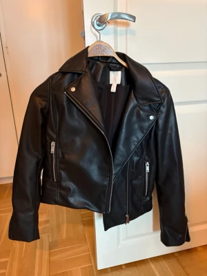 Svart skinnjacka med dragkedjor - Snygg svart skinnjacka från H&M med klassisk bikerstil. 
