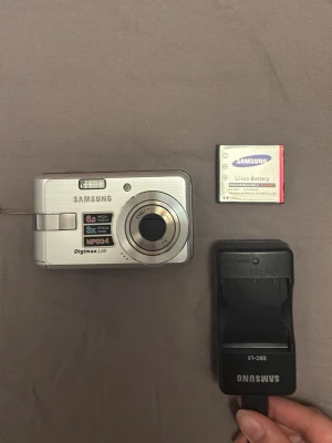 Samsung Digimax L60 digitalkamera - Jätte fin silvrig Samsung kamera. Allt medföljer förutom minneskort men går jätte lätt att köpa! Finns en defekt på skärmen MEN syns inte på bild eller påverkar dess funktion alls, se bild 3. 