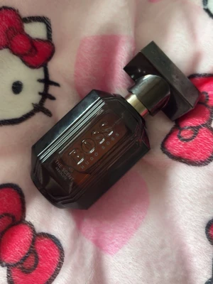 BOSS The Scent Absolute parfym - En elegant parfym från Hugo Boss, The Scent Absolute, i en mörkbrun glasflaska med geometrisk form och kraftigt lock. Flaskan har tydlig logga och ger ett lyxigt intryck. Perfekt för dig som gillar exklusiva dofter och snygg design. Se bild för mängd, urs 30ml, nu ca 15-17ml. En kryddig lyxig doft , köpt som parfym för kvinnor kan säkert vara unisex💛liten extra gåva vid varje köp! Skickar allt omsorgsfullt i bubbelplast & kartong.