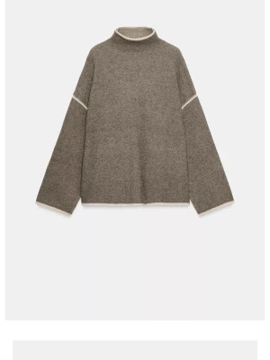 Brun stickad tröja med kontrastdetaljer - Säljer en oversized brun stickad tröja med hög hals och vita kontrastdetaljer vid hals, ärmslut och överarmar. Tröjan har vida ärmar och rak passform, perfekt för lager på lager. Materialet ser ut att vara mjukt och mysigt, troligen ullblandning.
