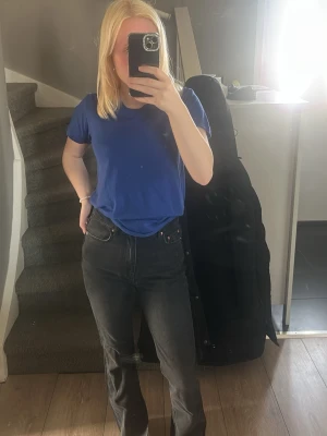 Svarta raka jeans med hög midja - Säljer ett par svarta jeans med rak passform och hög midja. Jeansen har klassiska fem fickor och bälteshällor. Snygg och enkel design som passar till det mesta. Materialet är denim i bomull. Perfekta för dig som gillar en clean och tidlös look.