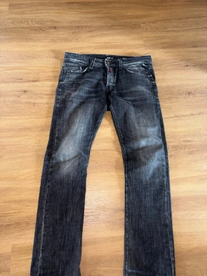 Replay Waitom - Snygga svarta Replay jeans med raka ben och slitna detaljer på framsidan och baksidan. Jeansen har klassisk femficksmodell och kontrastsömmar. Perfekta för en avslappnad streetstil. W30 L32