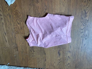 Ljusrosa ärmlös tränings topp - Säljer en enkel och stilren ljusrosa topp i mjukt material. Toppen är ärmlös och har en rak passform som passar perfekt till både jeans och kjol. Perfekt för vanlig outfit eller som träningströja.