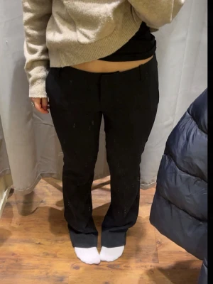 Svarta kostymbyxor med rak passform - Säljer ett par svarta kostymbyxor med rak passform och klassisk midja. Byxorna har diskreta fickor fram och är perfekta för en stilren look. Materialet känns mjukt och följsamt, troligen en blandning av polyester och viskos. Lite nopprig men inget man tänker på och går säkert bort med noppermaskin!🥰