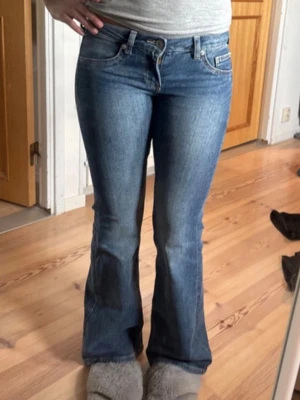 Blå bootcut jeans med låg midja - Säljer ett par klassiska blå bootcut jeans med låg midja ifrån Hm i storlek 32. Jeansen har två bak fickor och två fejk fickor på framsidan. Perfekta för en avslappnad och trendig look. 