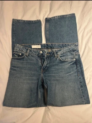Blå raka jeans från Zara - Klassiska blå jeans från Zara med rak passform och fem fickor. Jeansen har låg midja, gylf med dragkedja och knapp samt bälteshällor. Tillverkade i denim av bomull. Perfekta för en avslappnad och trendig look.