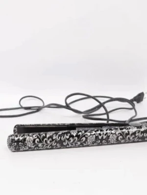 GHD plattång - Snygg plattång i svart med vit blommig dekor och lång sladd. Perfekt för att styla håret och skapa släta eller lockiga frisyrer. Smal och smidig design som gör den enkel att använda och ta med sig.