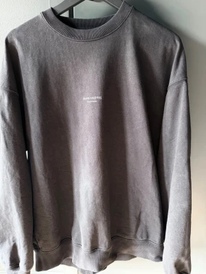 Svart sweatshirt från Acne Studio, storlek S - Svart sweatshirt från Acne Studios med diskret logga på bröstet. Tröjan har rund halsringning, långa ärmar och ribbade muddar vid ärmslut och nederkant. Perfekt för en avslappnad och stilren look.