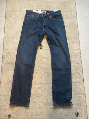Grant jeans - Klassiska blå Grant jeans med rak passform och fem fickor. Perfekta för en avslappnad och tidlös stil. Storlek : 34/32 regular fit. Aldrig använda.