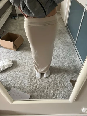 Maxikjol - Säljer en stilren beige långkjol med figurnära passform, med scrunch på sidan. Kjolen är enkel och enfärgad, tillverkad i ett mjukt och material. Perfekt för dig som gillar minimalistisk stil. 
