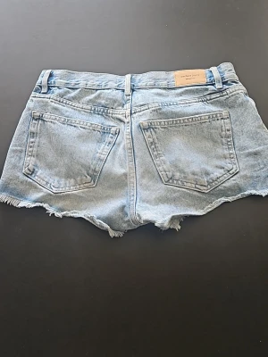 Ljusblå jeansshorts från Perfect Jeans - Snygga ljusblå jeansshorts från Perfect Jeans med råa kanter och klassiska bakfickor. Shortsen har en avslappnad passform och är perfekta för varma dagar. Tillverkade i bomull för en skön känsla.