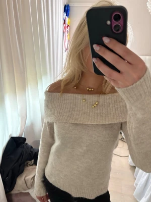 Beige off shoulder stickad tröja - Snygg beige stickad tröja med off shoulder-design och bred krage. Tröjan har långa ärmar och är ribbstickad vid ärmslut och nederkant. Knappt använd storlek 170 men passar S 