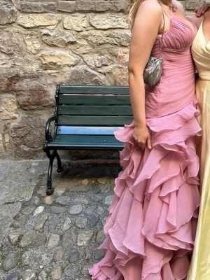 Rosa volangklänning - Säljer en lång, ljusrosa balklänning med volanger och sweetheart-ringning. Klänningen har figurnära överdel. Perfekt för bal eller festliga tillfällen.