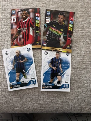 Fyra fotbollssamlarkort Topps/Panini - Fyra fotbollssamlarkort från Topps och Panini med spelare i olika lagtröjor. Korten har färgstarka tryck, spelarstatistik och klubbmärken. Perfekt för samlare eller fotbollsintresserade. Korten är i standardformat och gjorda av kartong.