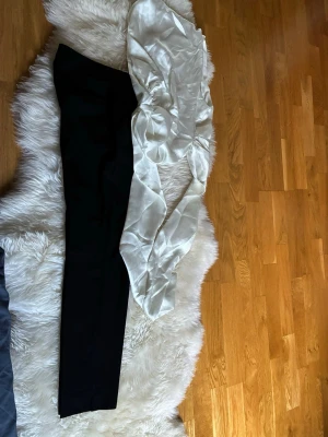 Vit satinsblus med puffärm - Snygg vit blus i glansigt satinmaterial med långa puffärmar och rynkade detaljer längs ärmarna. Perfekt för dig som vill ha en trendig och elegant look. Blusen har en feminin siluett och känns lyxig tack vare materialet.
