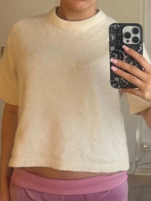 Krämvit stickad kortärmad topp - Säljer en krämvit stickad topp med korta ärmar och rund hals. Toppen har en enkel och clean look med ribbade kanter vid hals och ärmslut. Perfekt för dig som gillar en avslappnad men ändå stilren vibe. 💕.